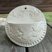 Load image into Gallery viewer, Round ceramic wall hanging with fish design on a wooden surface