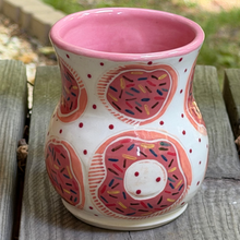 Load image into Gallery viewer, Pink sprinkle donut pottery mug sitting on a wooden porch.