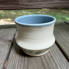 Load image into Gallery viewer, Pottery drink tumbler with light blue interior and white and bullseye design on outside.