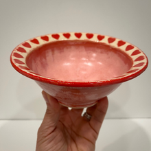 Load image into Gallery viewer, Hand holding a pink ceramic bowl with red decorative rim against a white background