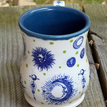 Load image into Gallery viewer, Ceramic mug with celestial designs on a wooden surface