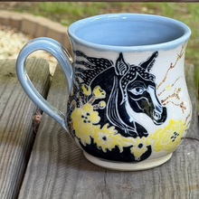 Load image into Gallery viewer, Black horse pottery mug hand painted and hand carved with light blue interior.
