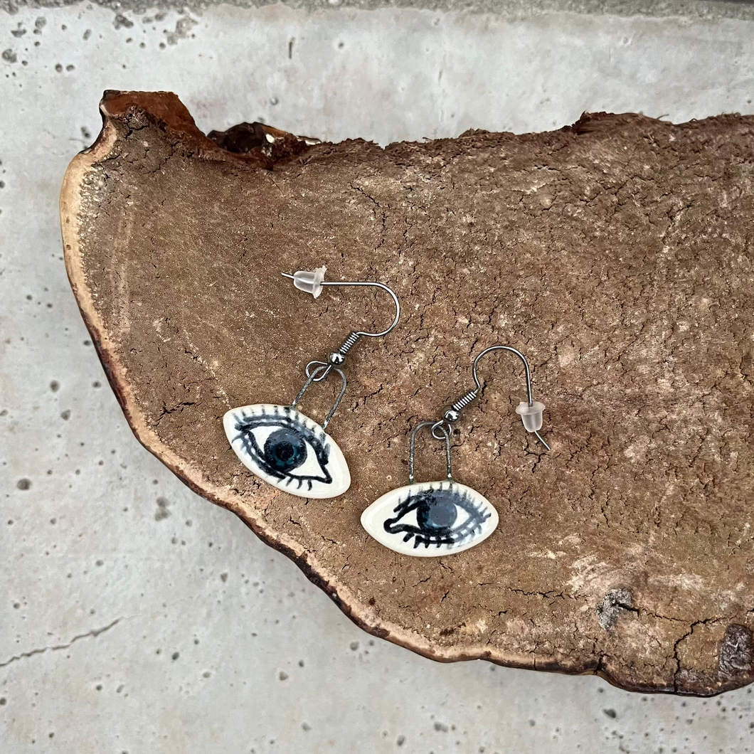 Eyeball-themed earrings on a rustic surface