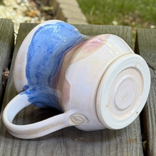 Load image into Gallery viewer, Ceramic mug with blue and pink glaze on a wooden surface
