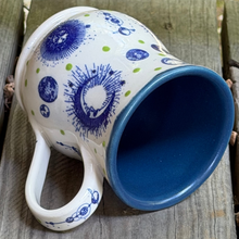 Load image into Gallery viewer, Celestial pottery mug laying on it's side with view of handle and inside.
