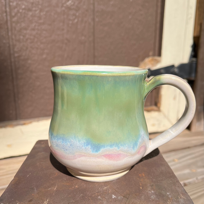 Green ceramic mug with a handle on a metal surface