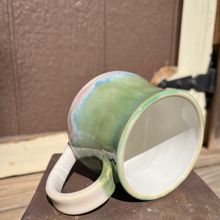 Load image into Gallery viewer, Green ceramic mug with a white interior on a metal surface

