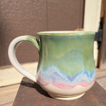 Load image into Gallery viewer, Ceramic mug with multicolored glaze on a metal surface
