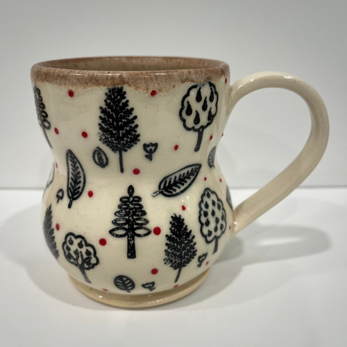 Ceramic mug with nature-themed pattern on a white background