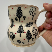 Load image into Gallery viewer, Ceramic mug with tree and leaf patterns held by a hand against a white background
