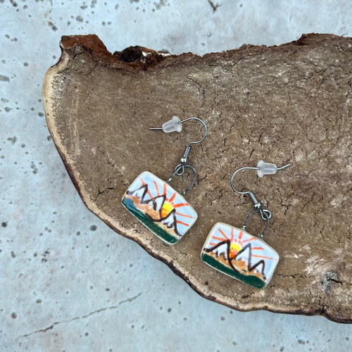Rectangular dangle clay earrings hand painted with a mountain scene.