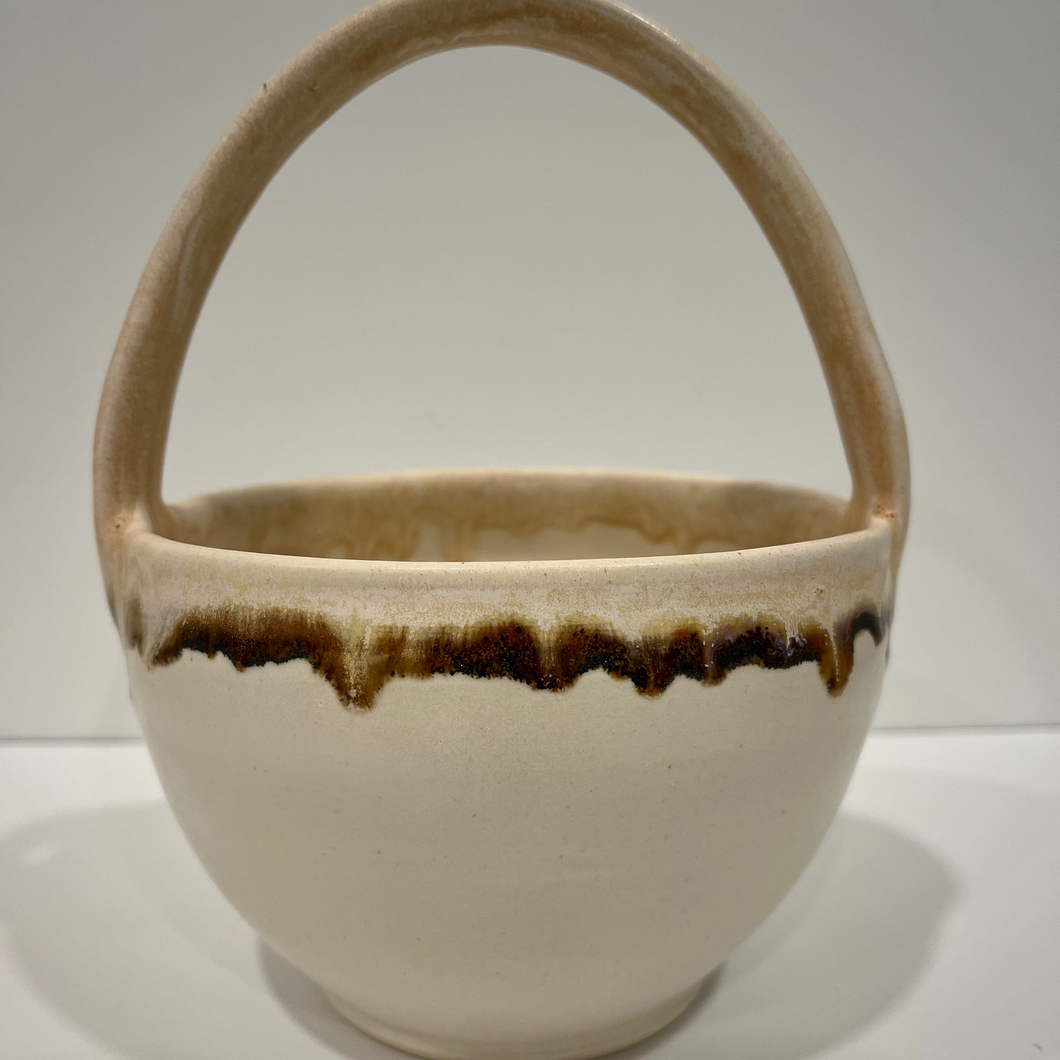Pottery basket in white, beige and brown on a white background.