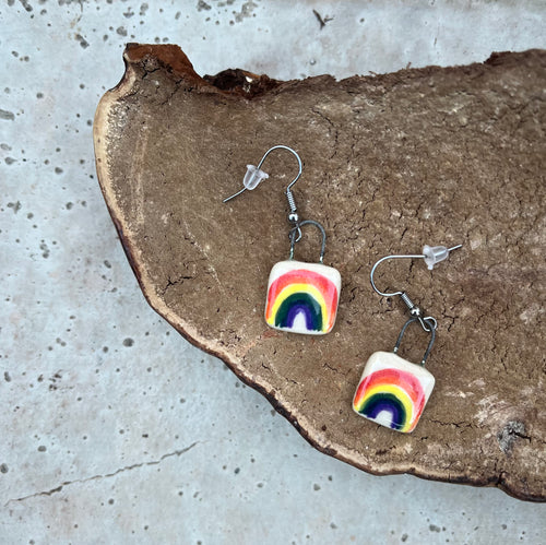 Square clay dangle earrings with hand painted rainbows and metal ear wires.