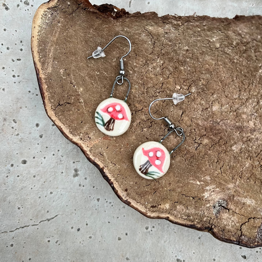 Red dot mushroom earrings on a mushroom background