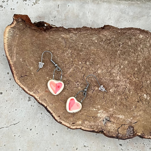 Heart-shaped earrings on a mushroom surface