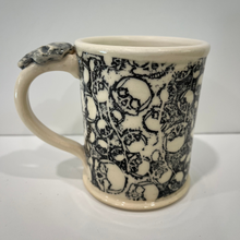 Load image into Gallery viewer, Pottery mug with black skull pattern on white background.
